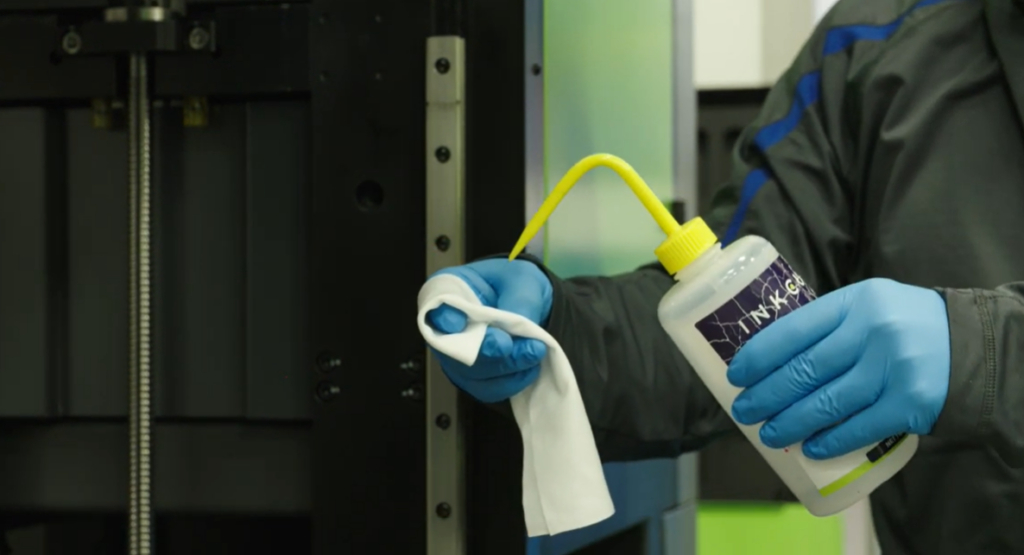 Inkcups Technician inspecting and performing maintenance on a UV flatbed printer